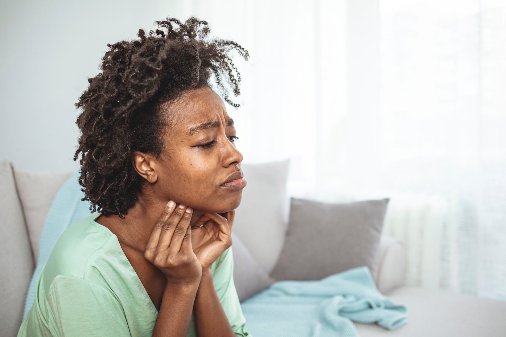 Woman holds her throat, sore throat.